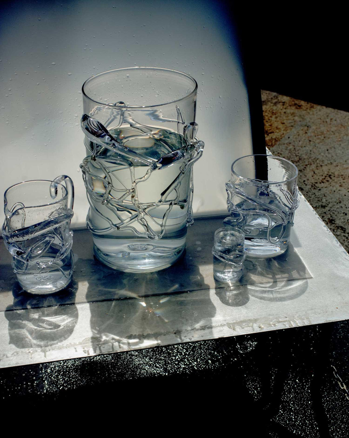 Vases with details of melted glass of different sizes and glasses shadow background