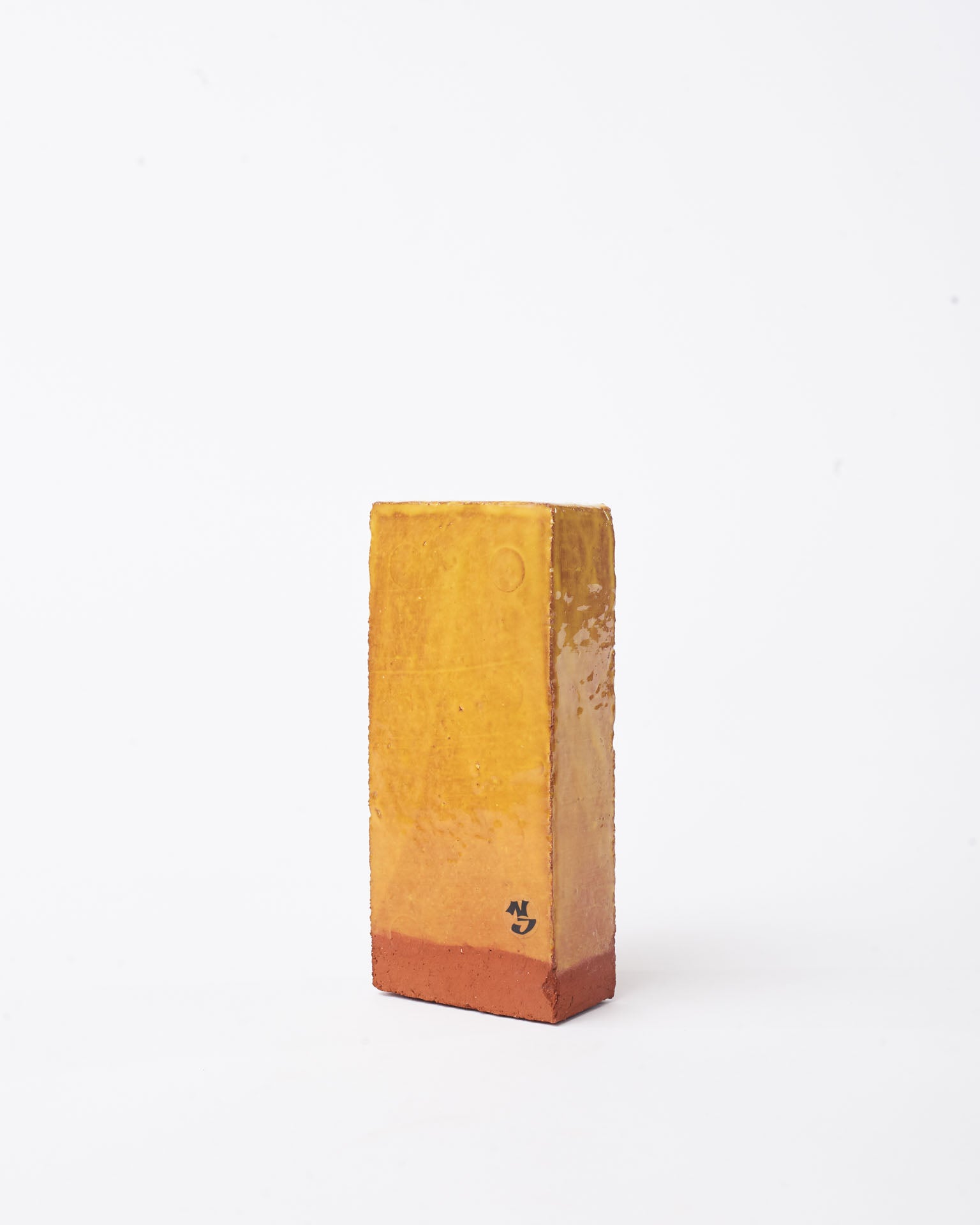 Handmade yellow brick ceramic candle holder in white glaze in background
