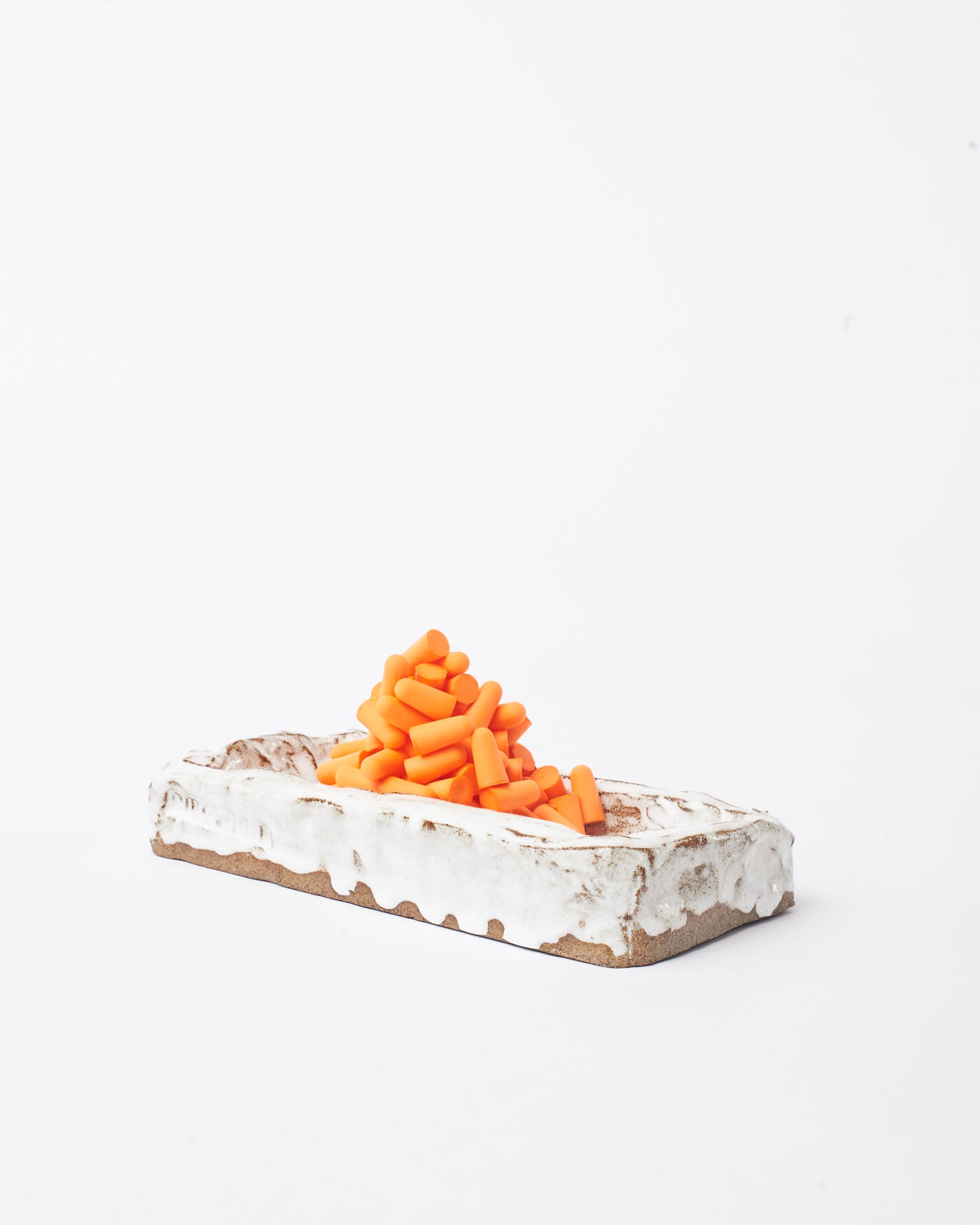 Handmade ceramic organizer object  white with tower earplug on the top in white background