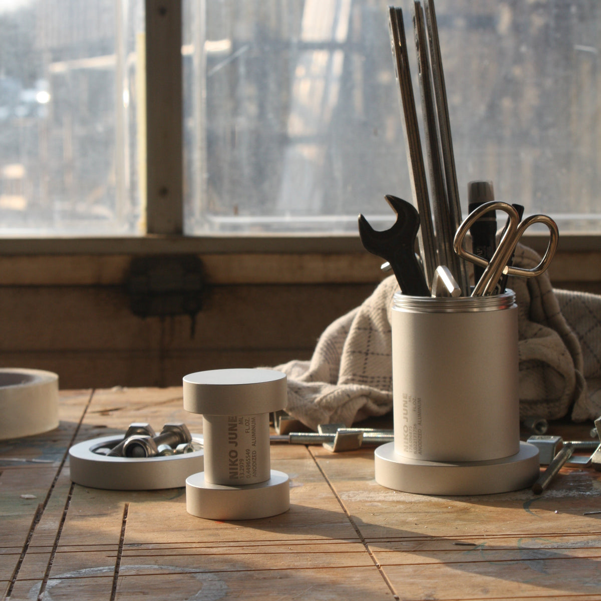 Chamber Series aluminium storage container by NIKO JUNE displayed on a wooden surface beside a window in a sunlit interior.