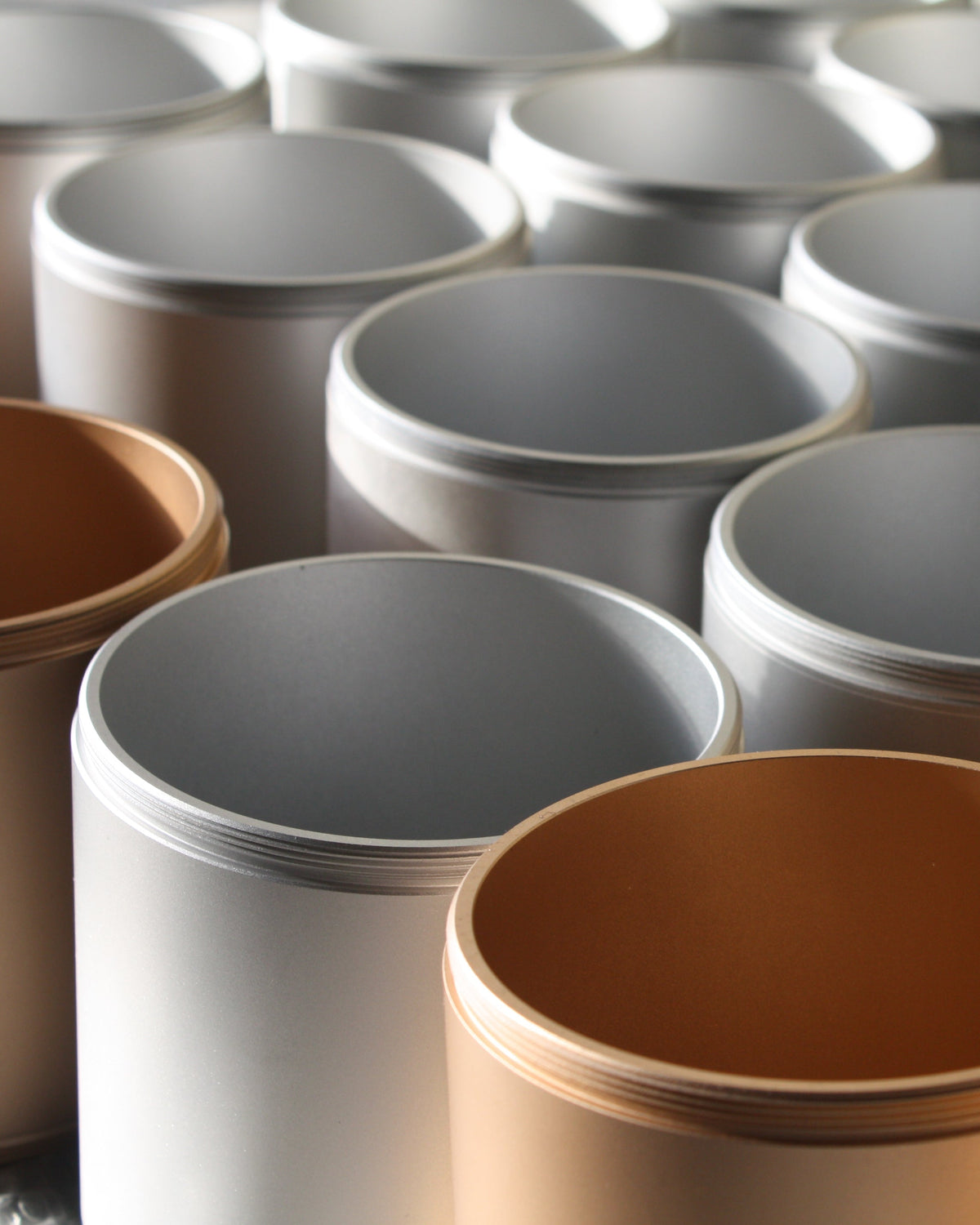Close-up of Chamber Series aluminium storage containers by NIKO JUNE in Grey and Gold, arranged together with their open cylindrical forms and anodized finishes visible.