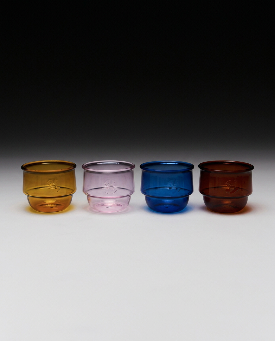 Four colourful Kantine Drinking Glasses by NIKO JUNE in yellow, pink, blue and amber, made from stackable borosilicate glass.