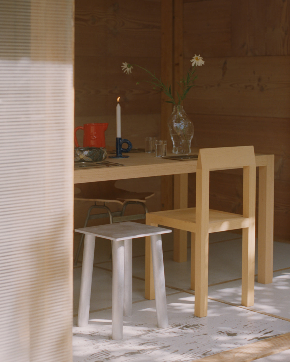Studio Candlestick Dark Blue by NIKO JUNE displayed on a wooden table in a minimalist interior with wooden chairs and natural materials.