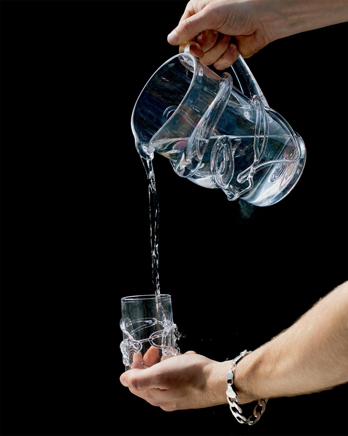 Hands holding hand blown glass with melted glass details on black background
